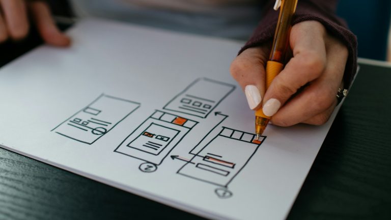 Hand sketching a website wireframe on paper