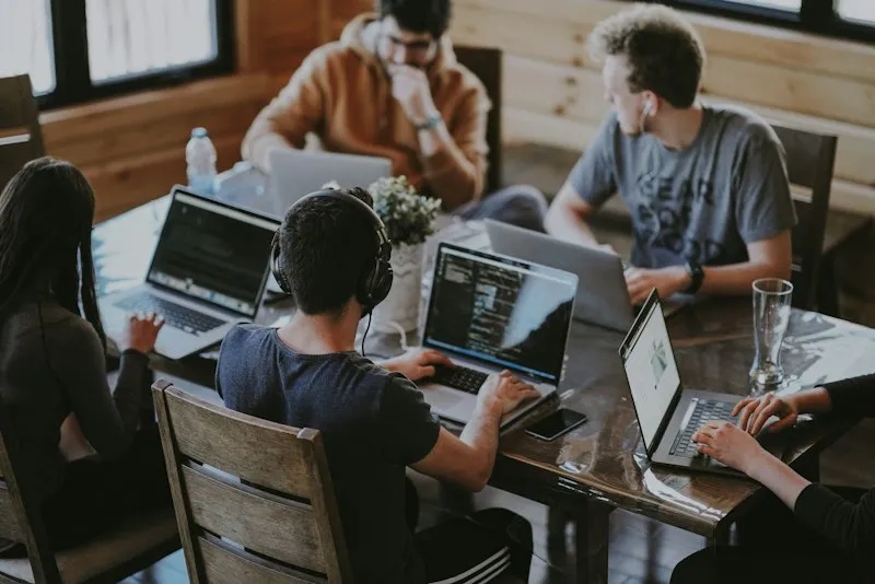 Four people working on laptops around a table